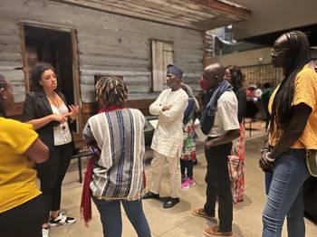 People gather around to listen to a speaking guide in a museum context